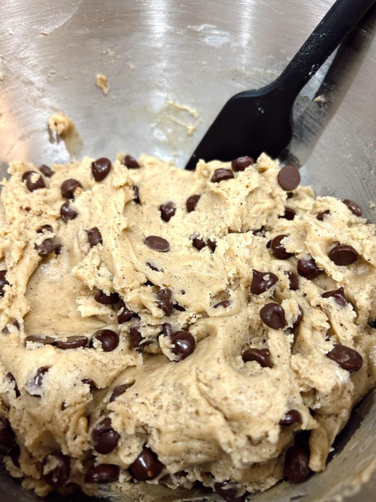 Chocolate chip cookie dough still in the bowl with a rubber spatula